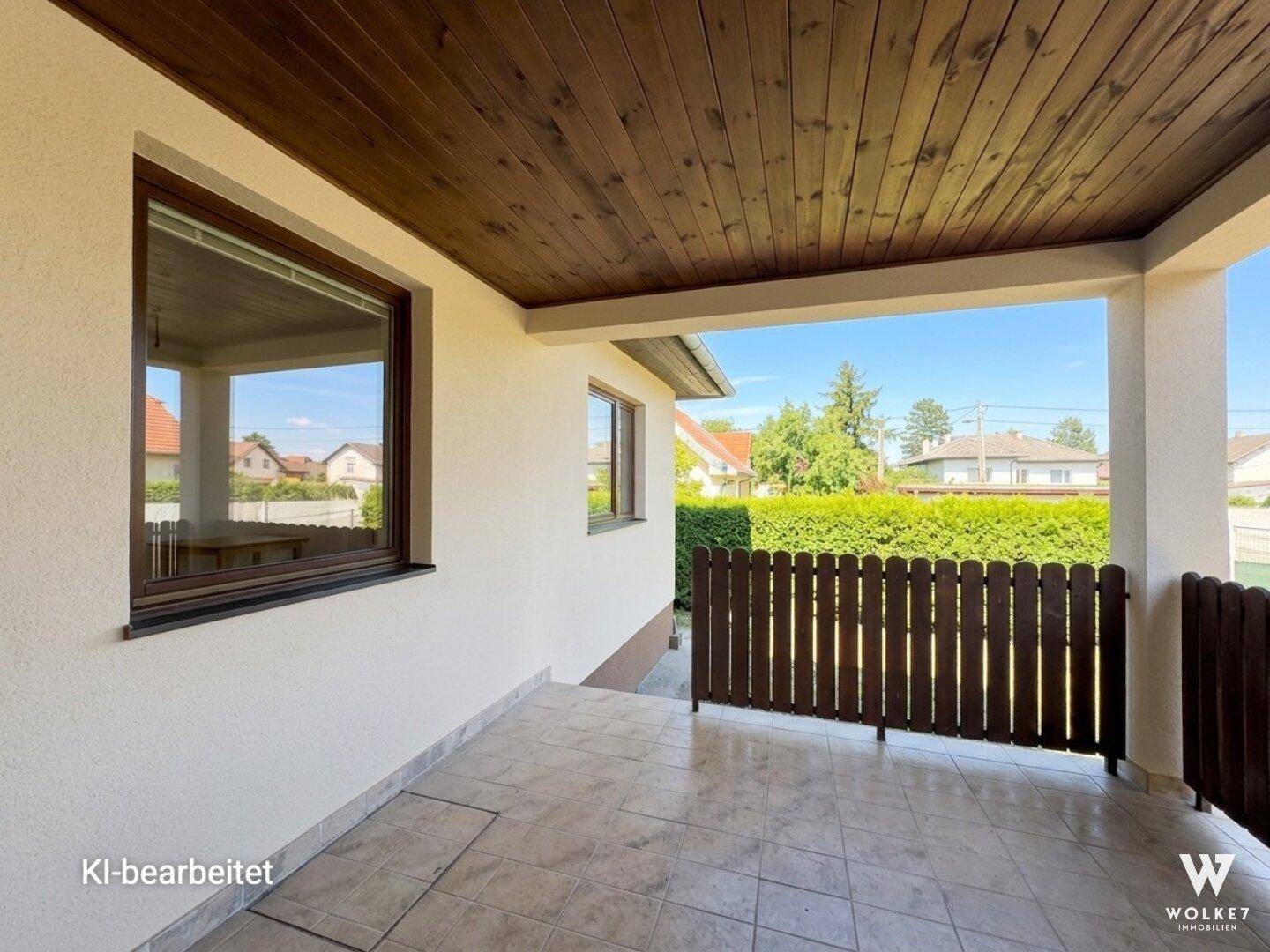 Überdachte Loggia mit Fliesenboden und Holzdecke, bietet einen geschützten Außenbereich.