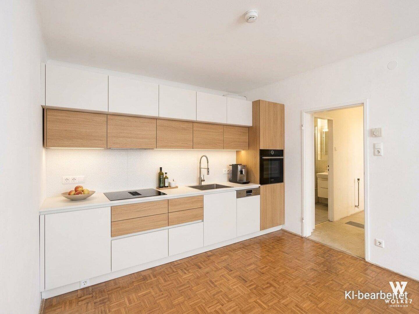 Moderne Einbauküche mit hellen Fronten und Holzdetails, ausgestattet mit Induktionskochfeld und Backofen.
