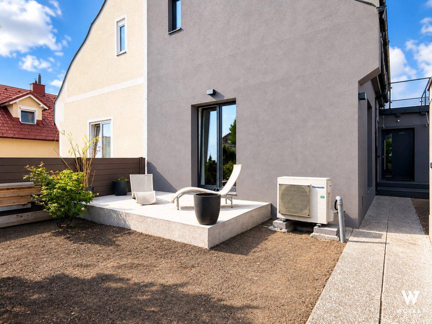 Gartenbereich mit vorbereiteter Fläche für Rasen und moderner Terrasse am Haus.