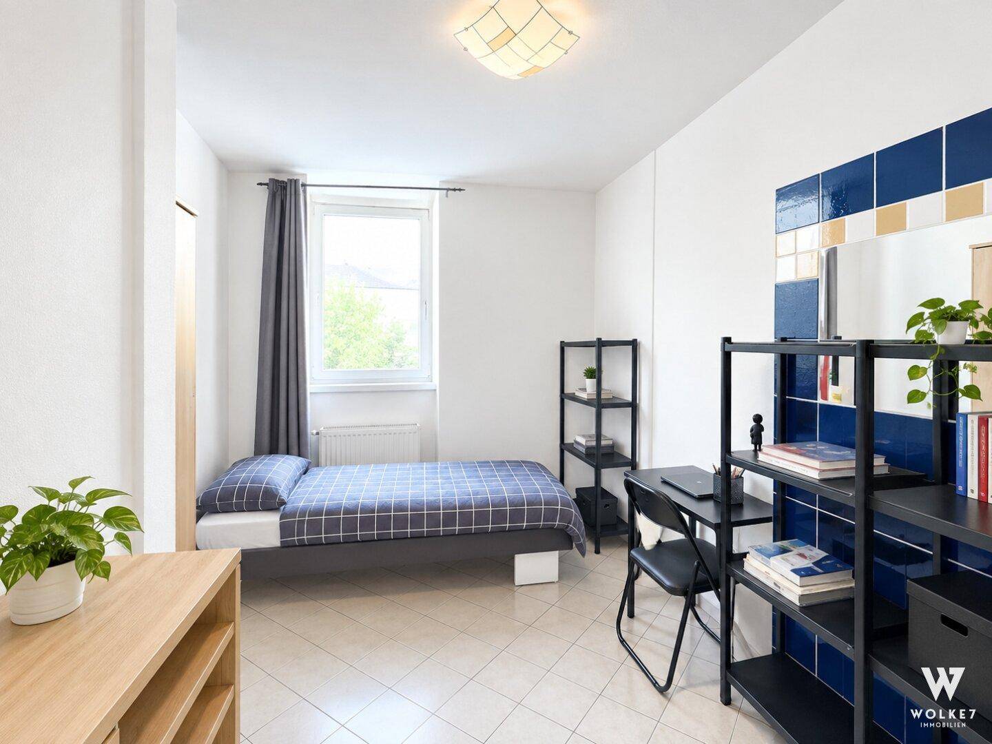 Funktionales Schlafzimmer mit Einzelbett, Schreibtisch und dekorativen Fliesen an der Wand.