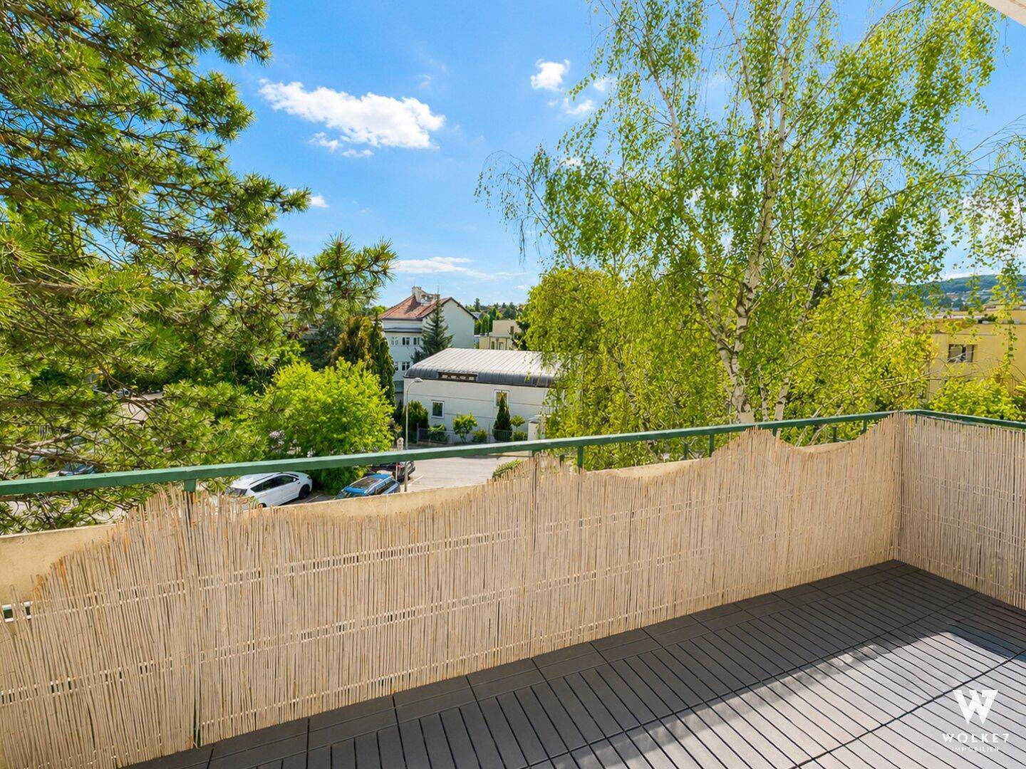 Balkon mit Bambus-Sichtschutz und Blick auf Bäume und die Umgebung.