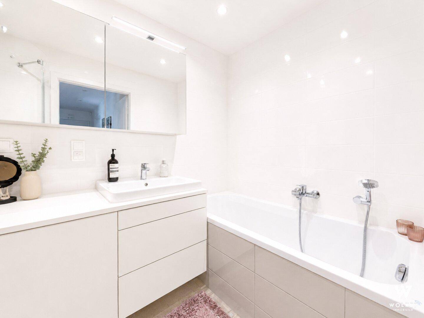 Modernes Badezimmer mit Badewanne, Einzelwaschbecken und Spiegelschrank.