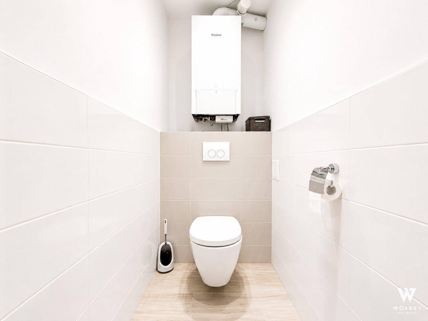 Separates WC mit wandhängender Toilette und Heizungsanlage.