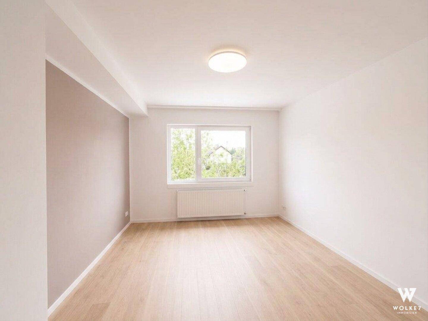 Helles, unmöbliertes Zimmer mit Akzentwand und Holzboden.