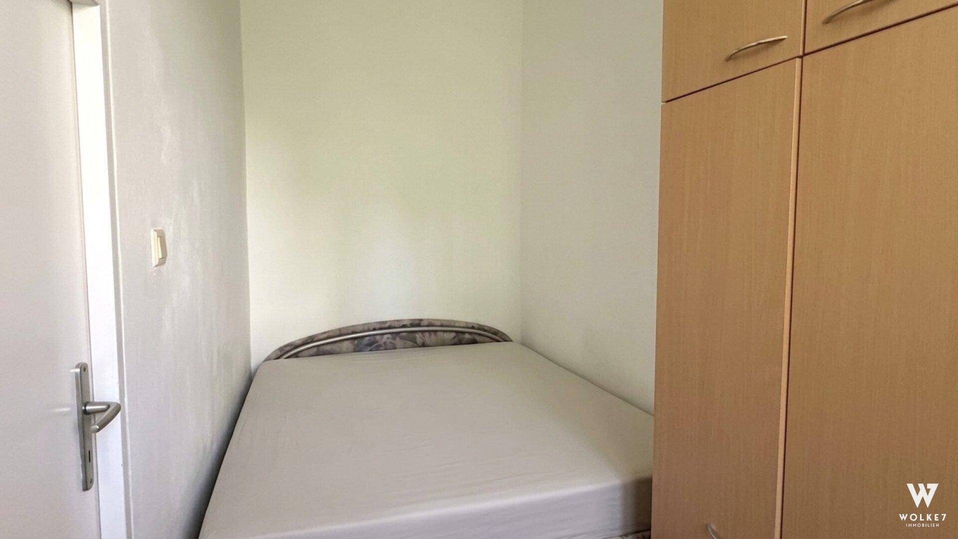 Kleines Schlafzimmer mit Einzelbett und Holzschrank, ideal als Kinder- oder Gästezimmer.