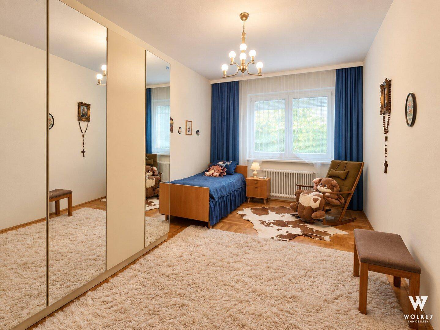 Kinderzimmer mit Einzelbett, Schreibtisch, Spiegelschrank und einem flauschigen Teppich.