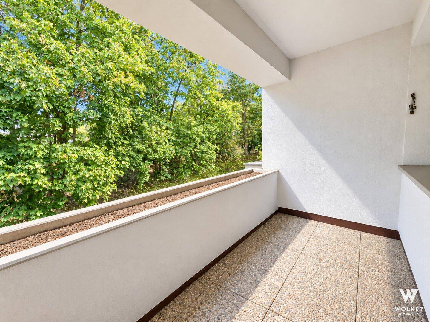 Heller Balkon mit Fliesenboden und einem schönen Blick ins Grüne.