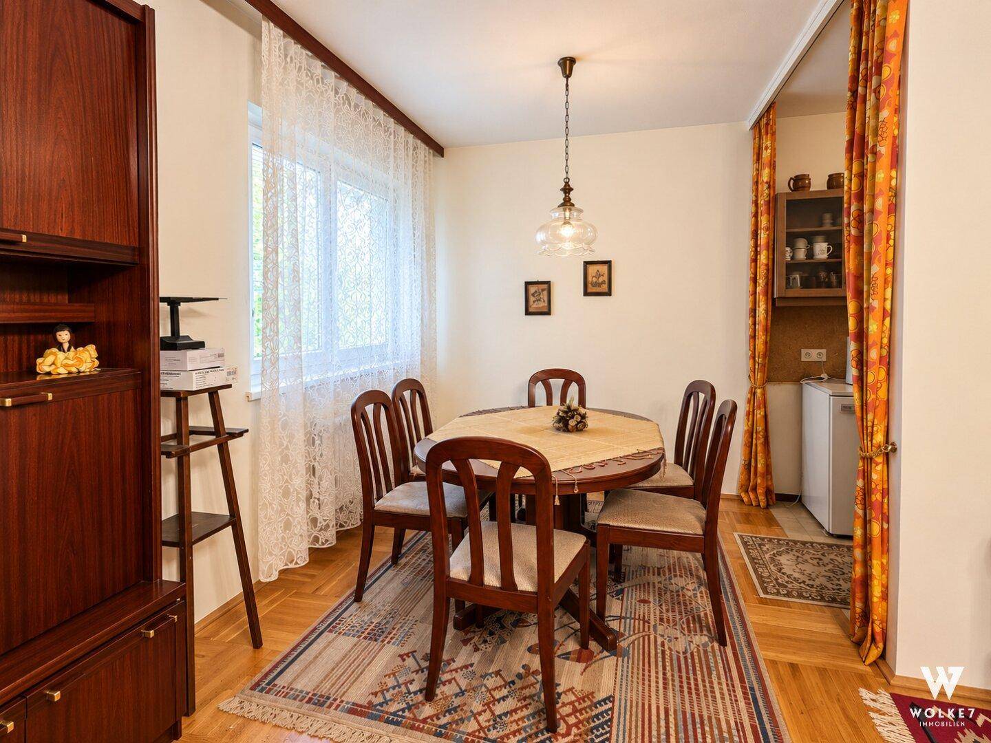 Gemütlicher Essbereich mit rundem Holztisch, Stühlen und einem traditionellen Holzschrank.