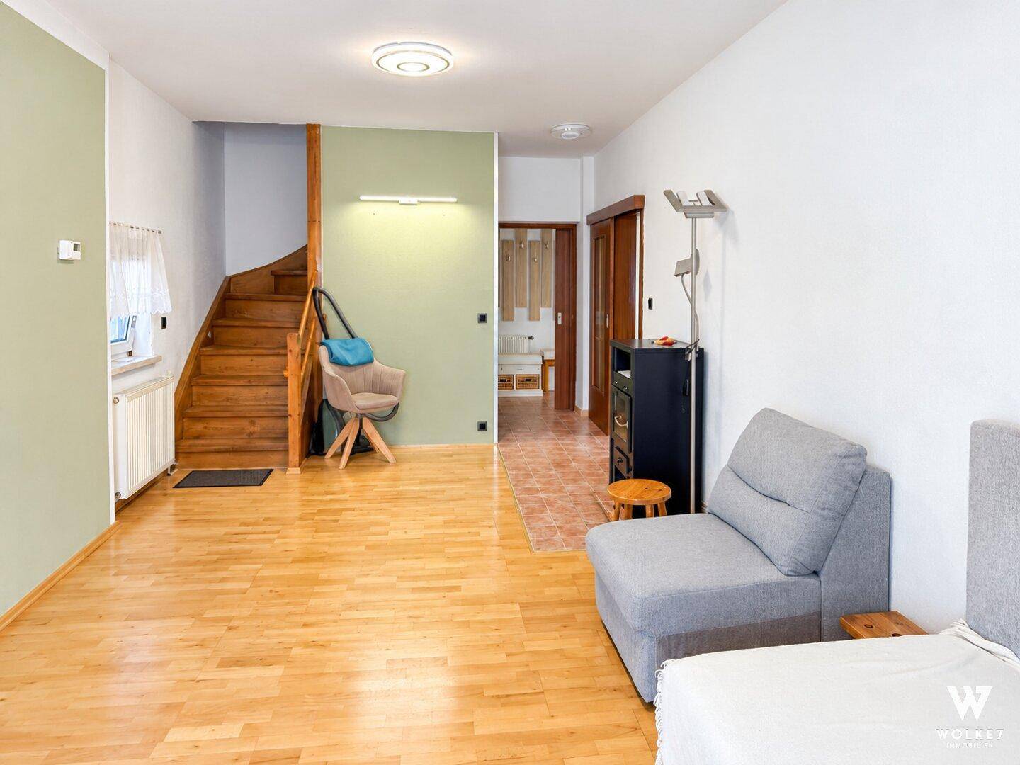Geräumiges Wohnzimmer mit Holztreppe, Parkettboden und Zugang zu weiteren Räumen.