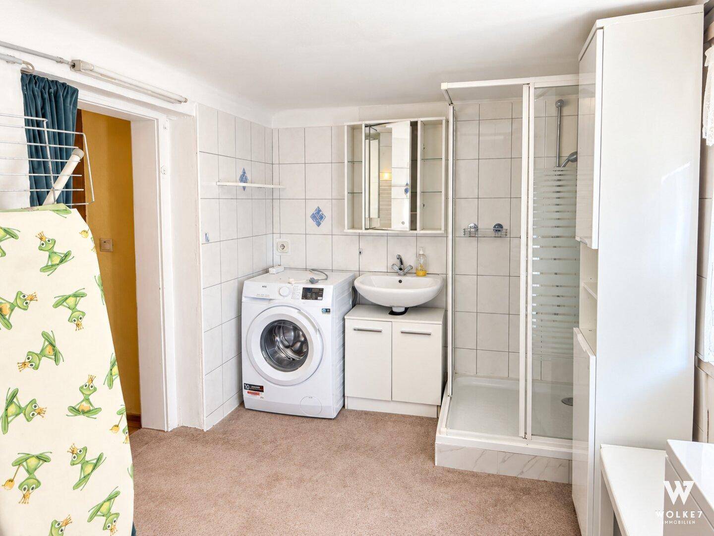 Helles Badezimmer im Keller mit Duschkabine, Waschbecken und praktischen Schränken.