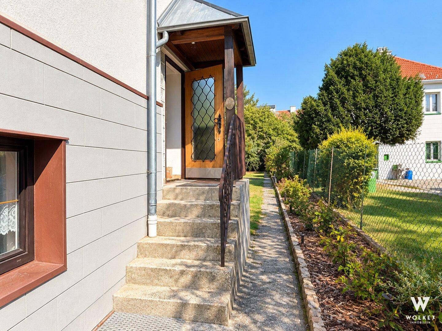 Eingangsbereich des Hauses mit überdachter Treppe und seitlichem Gartenweg.