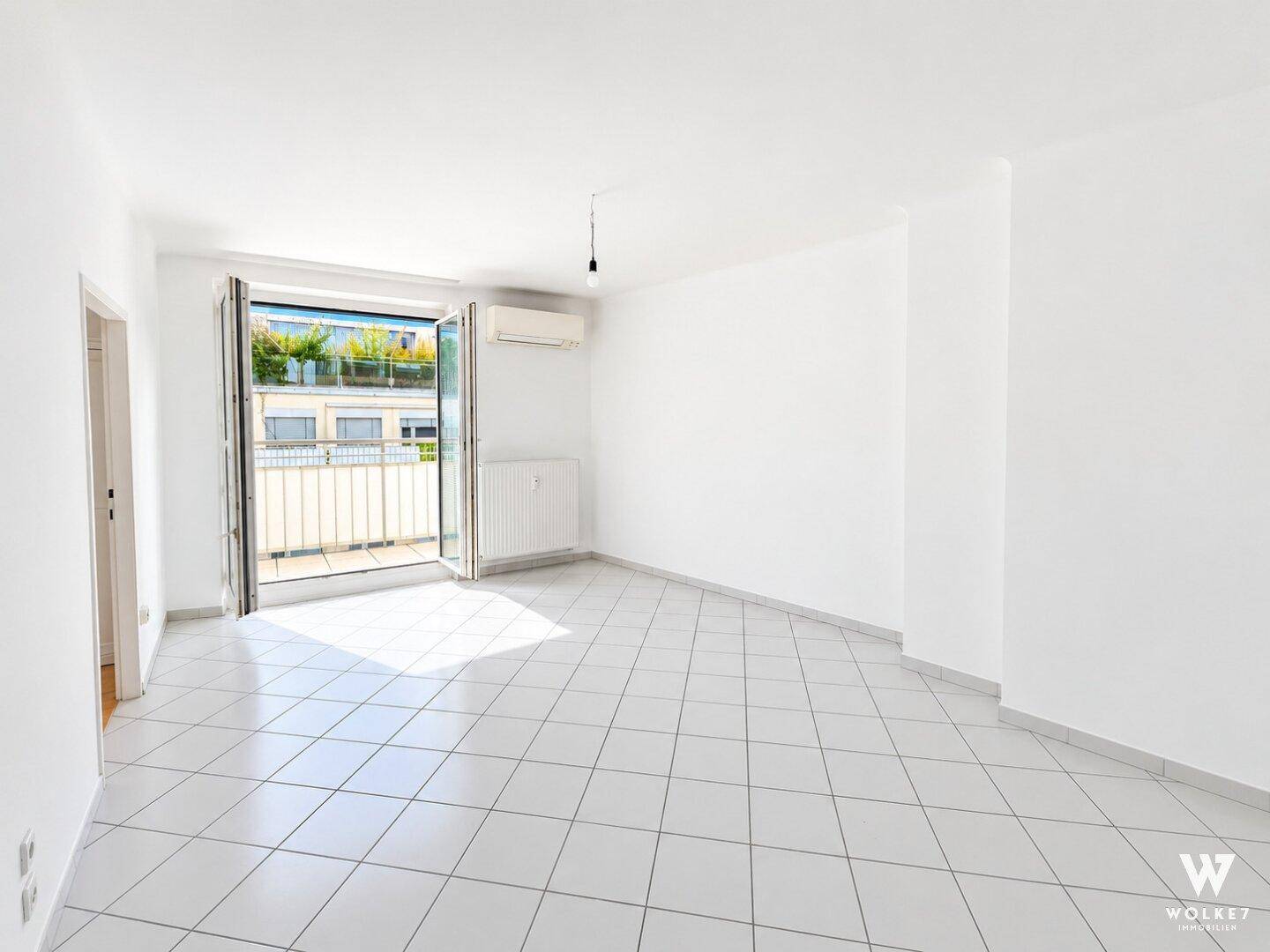 Geräumiger, heller Raum mit Fliesenboden, Klimaanlage und Zugang zu einem Balkon.