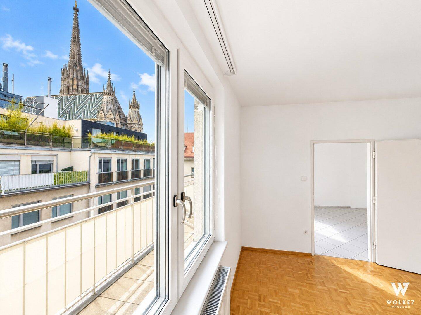 Helles Zimmer mit Parkettboden und Fenster mit beeindruckendem Blick auf den Stephansdom.