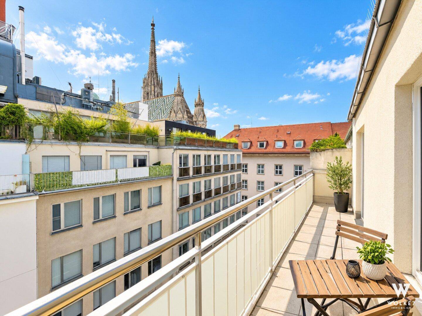 Geräumiger Balkon mit Sitzgelegenheiten und weitem Blick über die Stadt und den Stephansdom.
