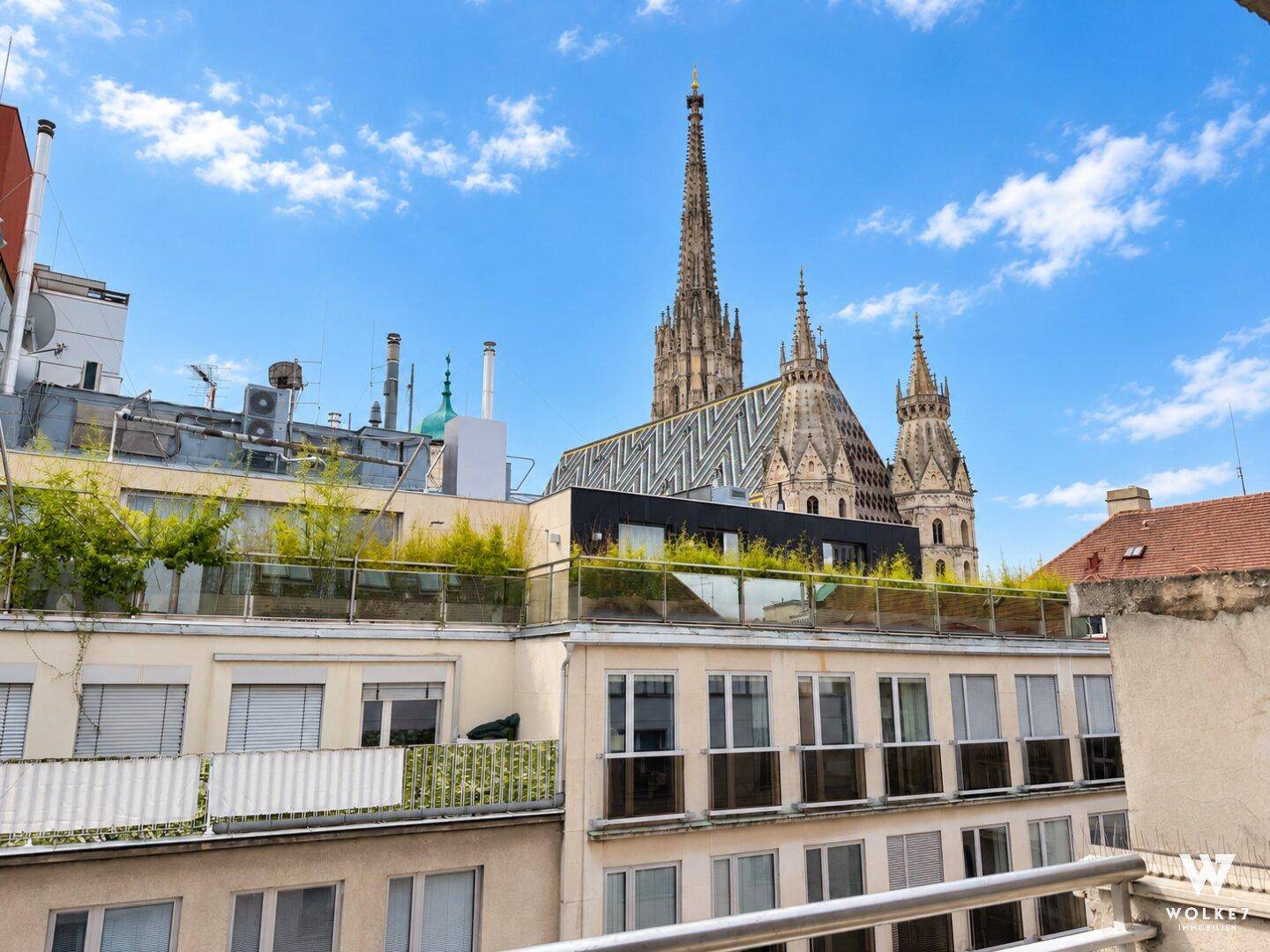 Panoramablick über die Stadt mit dem Stephansdom und umliegenden Gebäuden unter blauem Himmel.