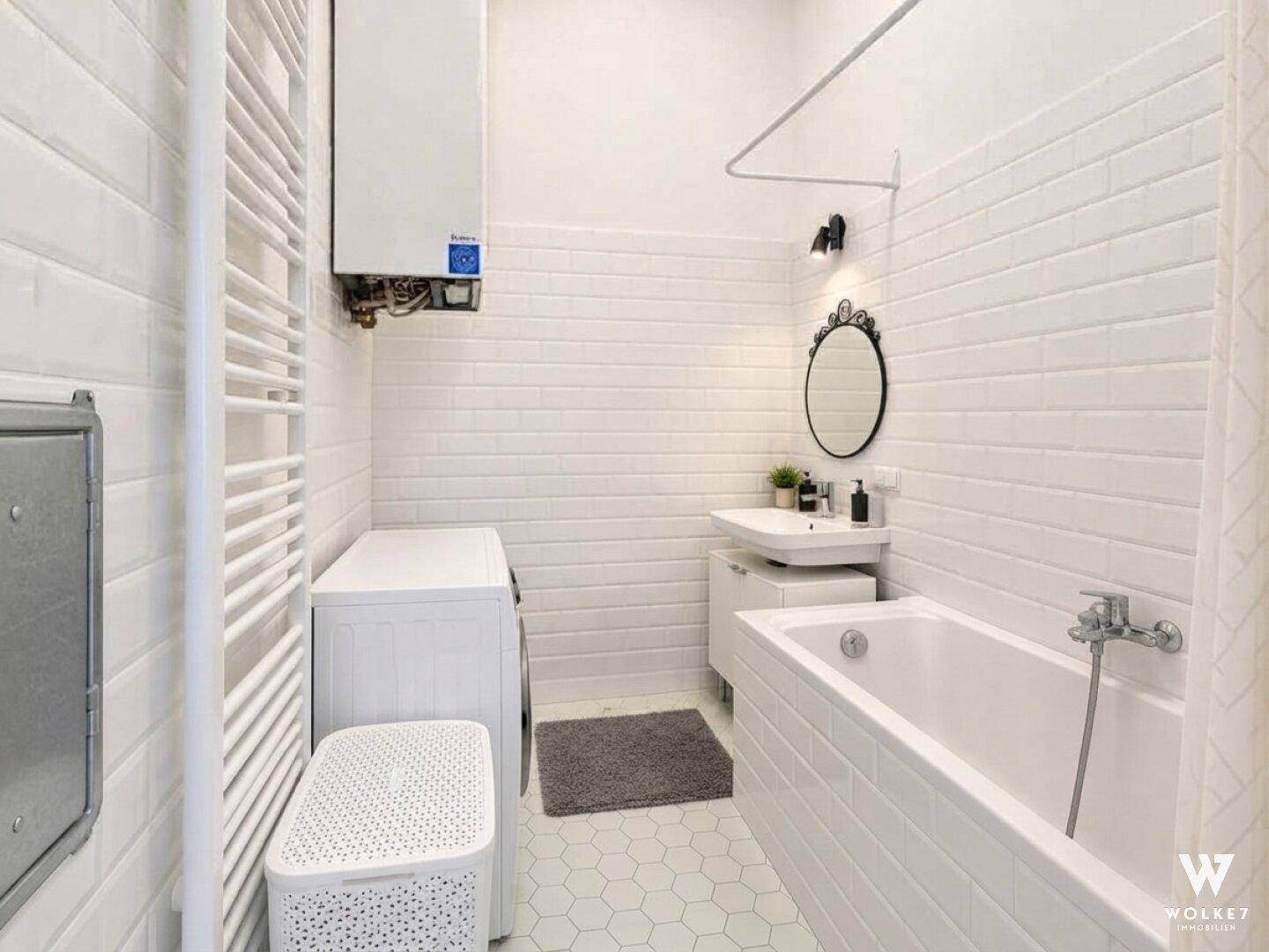 Modernes Badezimmer mit weißen Fliesen, Badewanne und Waschmaschine.