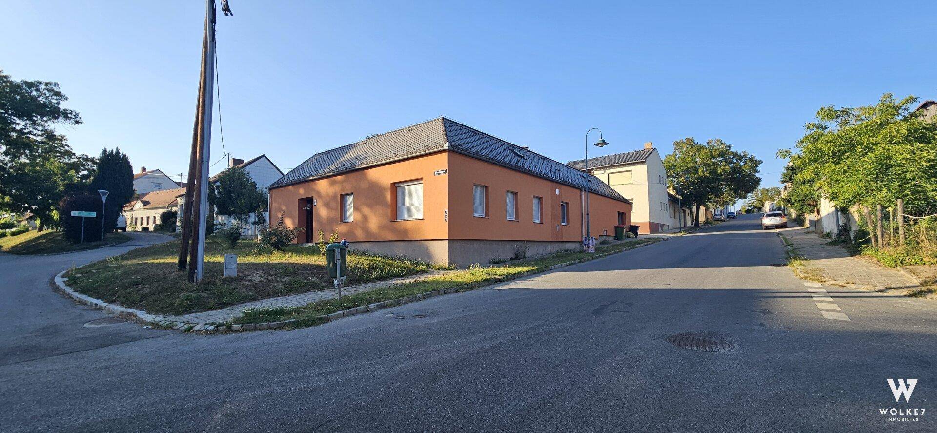 Ansicht des Hauses mit oranger Fassade an einer Straßenecke in ländlicher Umgebung.