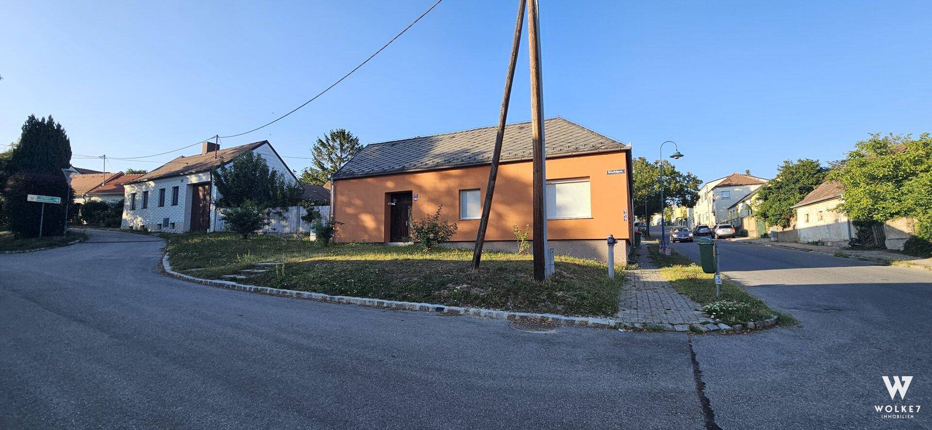Weitläufige Straßenansicht des orangefarbenen Hauses mit Satteldach in einer ruhigen Wohngegend.
