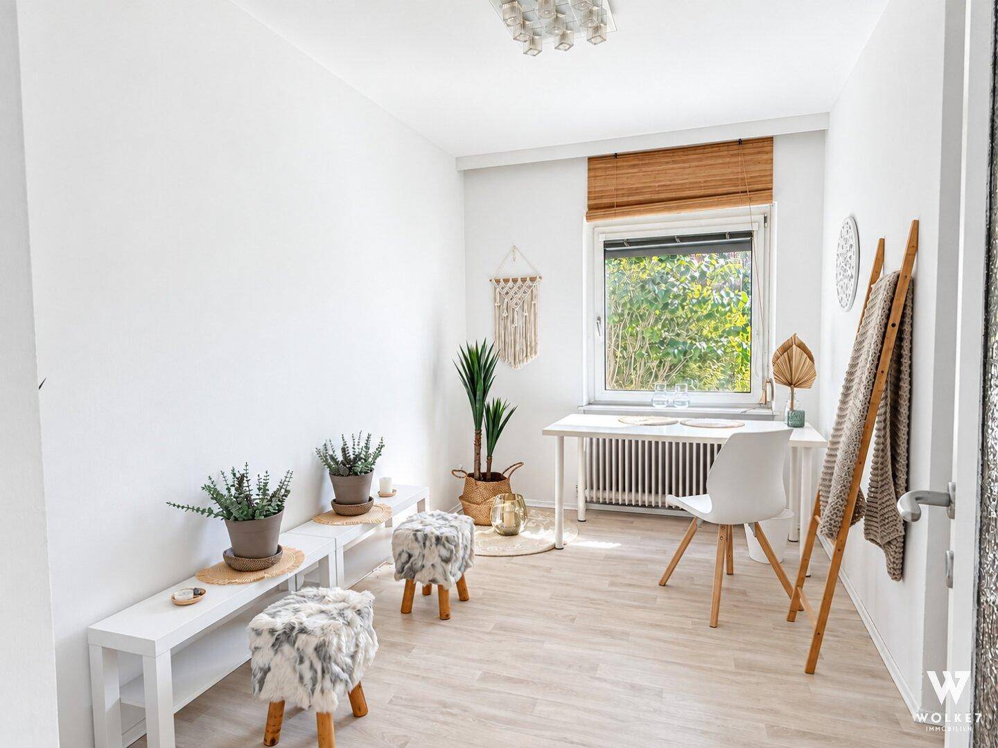 Ruhiges Arbeitszimmer mit Schreibtisch, Pflanzen und hellem Laminatboden, ideal für Home-Office.