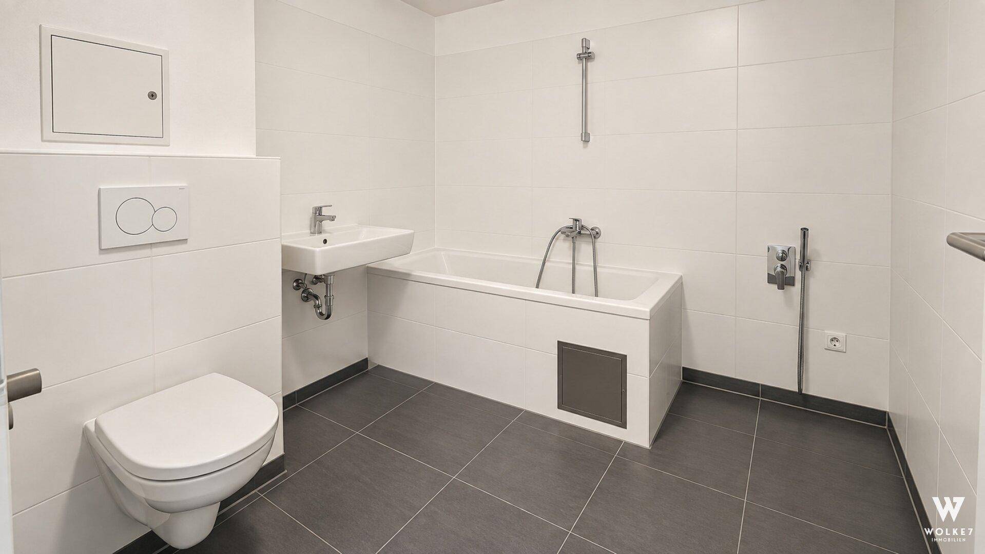 Modernes Badezimmer mit Badewanne, wandhängendem WC, Waschbecken und grauen Bodenfliesen.