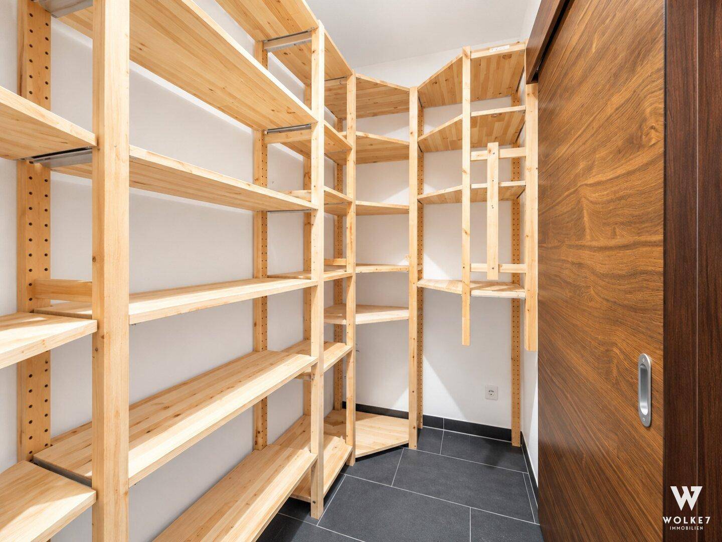 Praktischer Abstellraum mit vielen Holzregalen für Lagerung und Organisation.