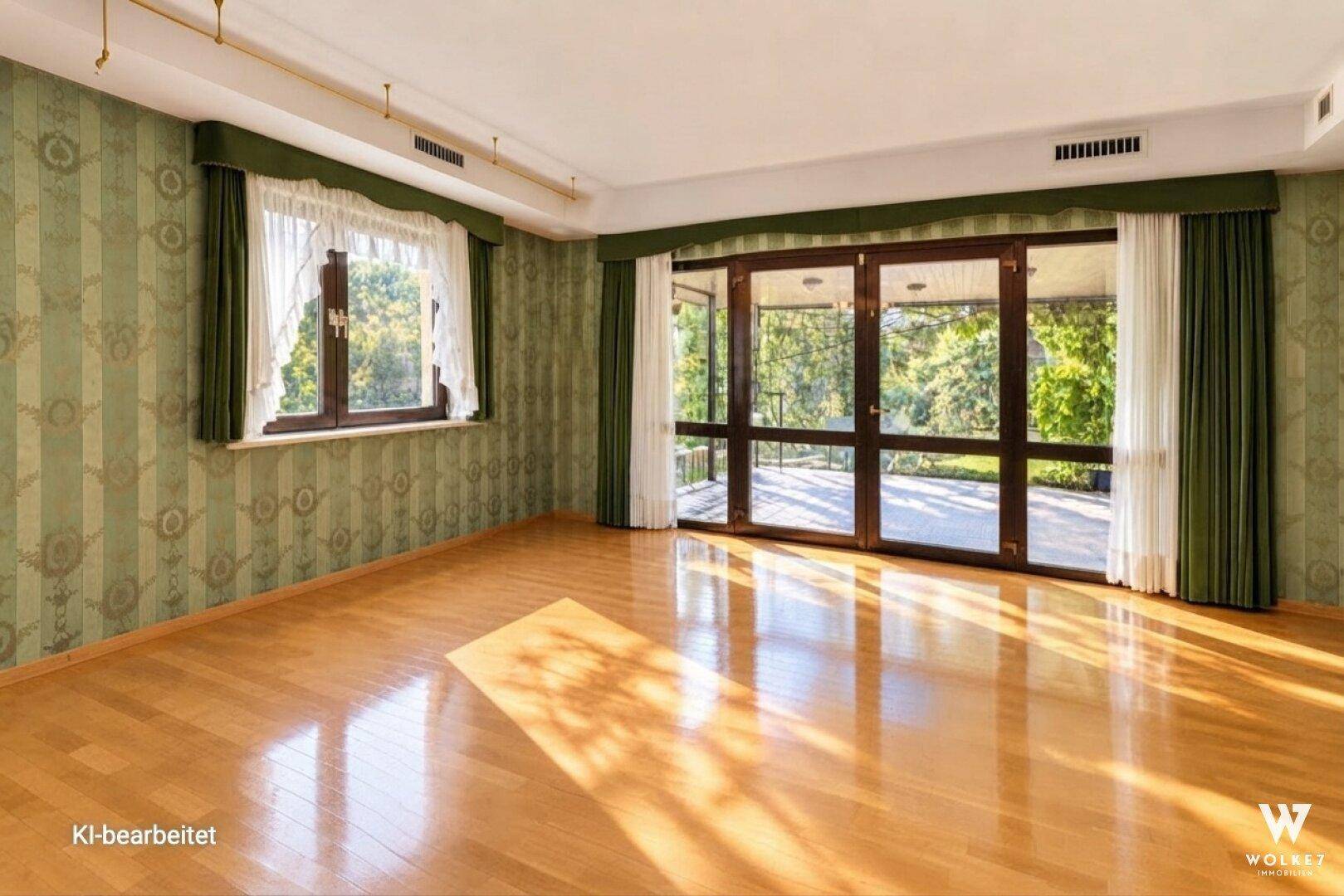 Geräumiges Zimmer mit grün gemusterter Tapete, Parkettboden und großen Fenstern, die viel Licht hereinlassen.