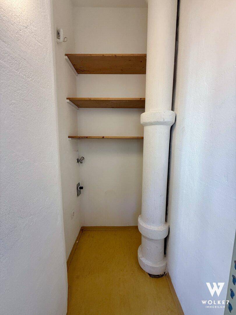 Praktischer Abstellraum mit Holzregalen und einer sichtbaren Versorgungsleitung.