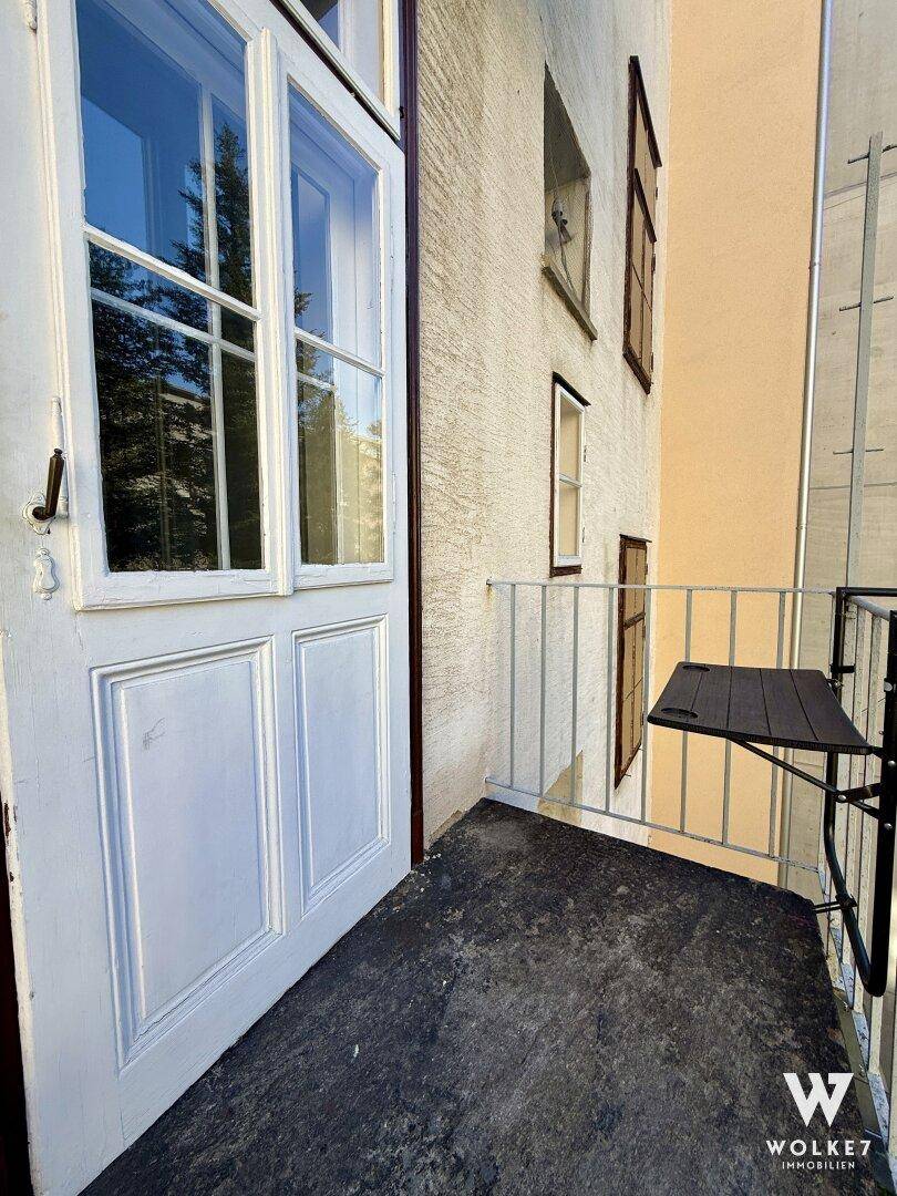 Zugang zum Balkon mit weißer Tür und einem kleinen, an der Brüstung befestigten Tisch.