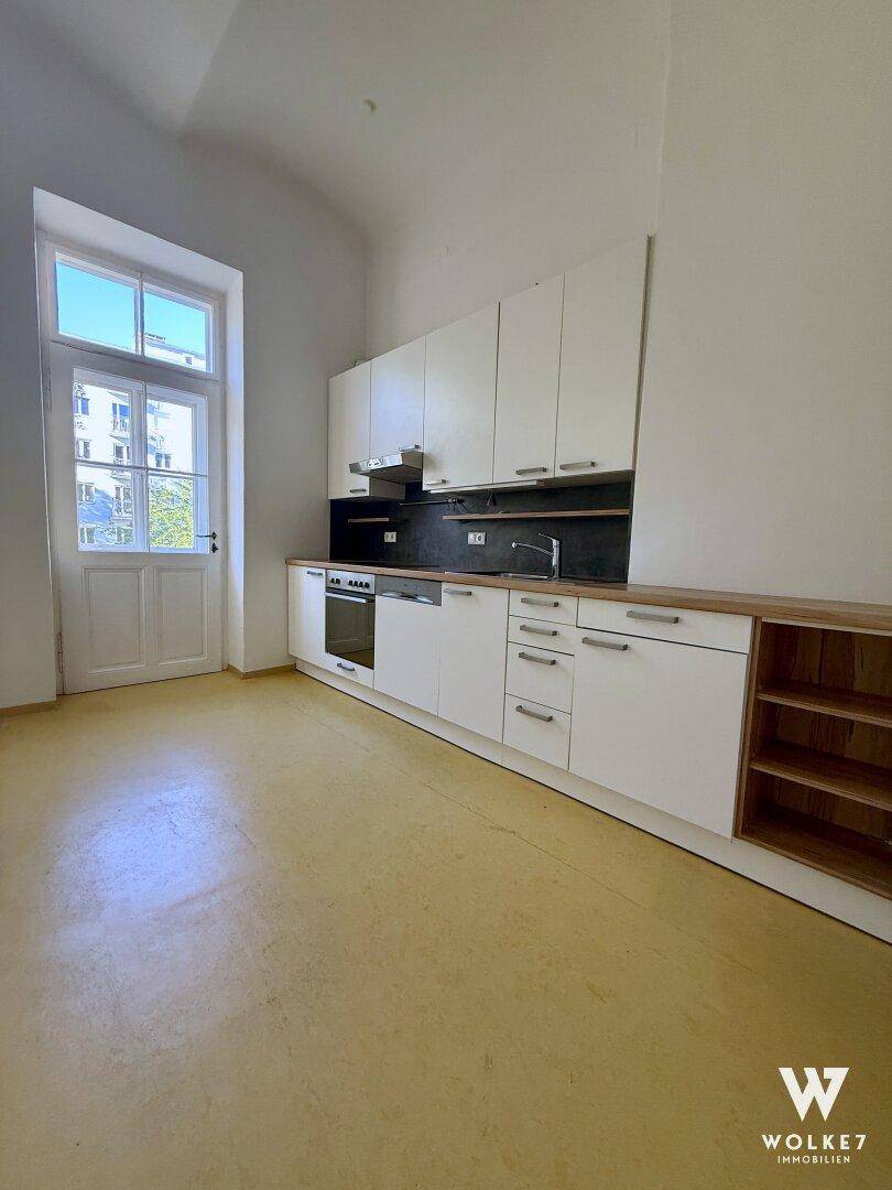 Helle Küche mit weißer Einbauküche, integriertem Backofen und Zugang zum Außenbereich.