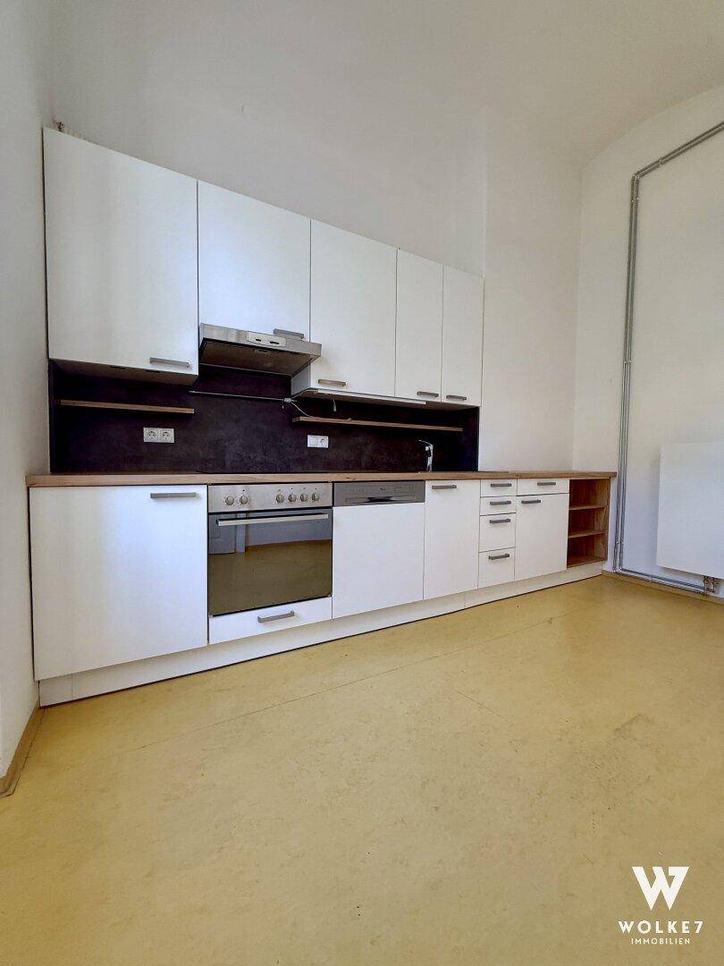 Detailansicht der modernen Einbauküche mit weißen Schränken, Backofen und Dunstabzugshaube.