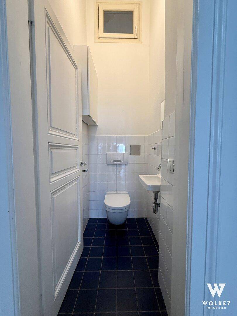 Funktionelles Gäste-WC mit Toilette, kleinem Waschbecken und Fenster für Tageslicht.