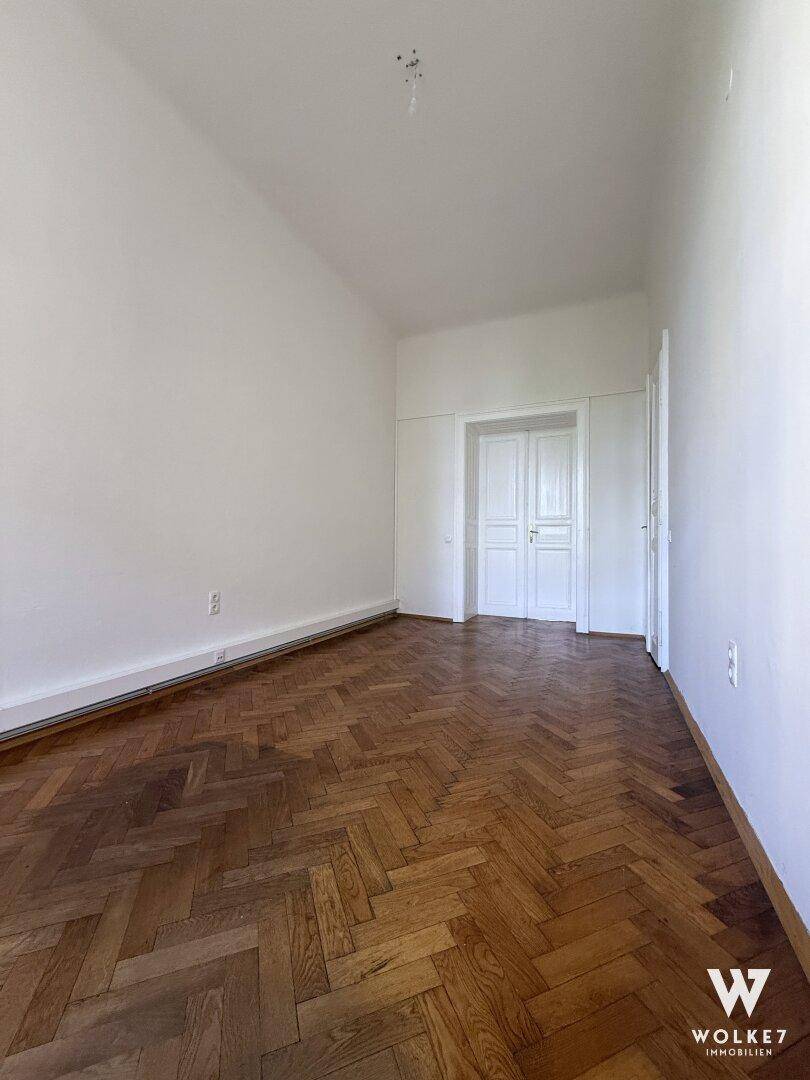 Helles Zimmer mit klassischem Fischgrätparkett und weißen Wänden, ideal für individuelle Einrichtung.