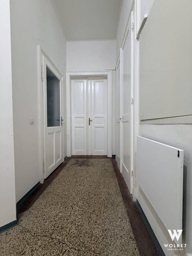 Heller Flur mit Teppichboden und mehreren weißen Türen, die zu den Zimmern führen.