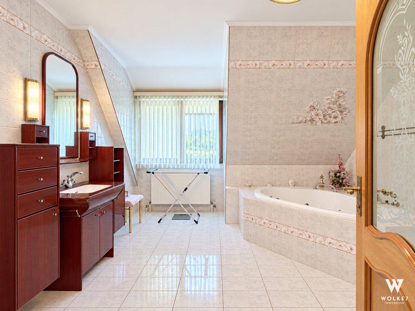 Geräumiges Badezimmer mit Eckbadewanne, großem Waschtisch und Fliesenboden.