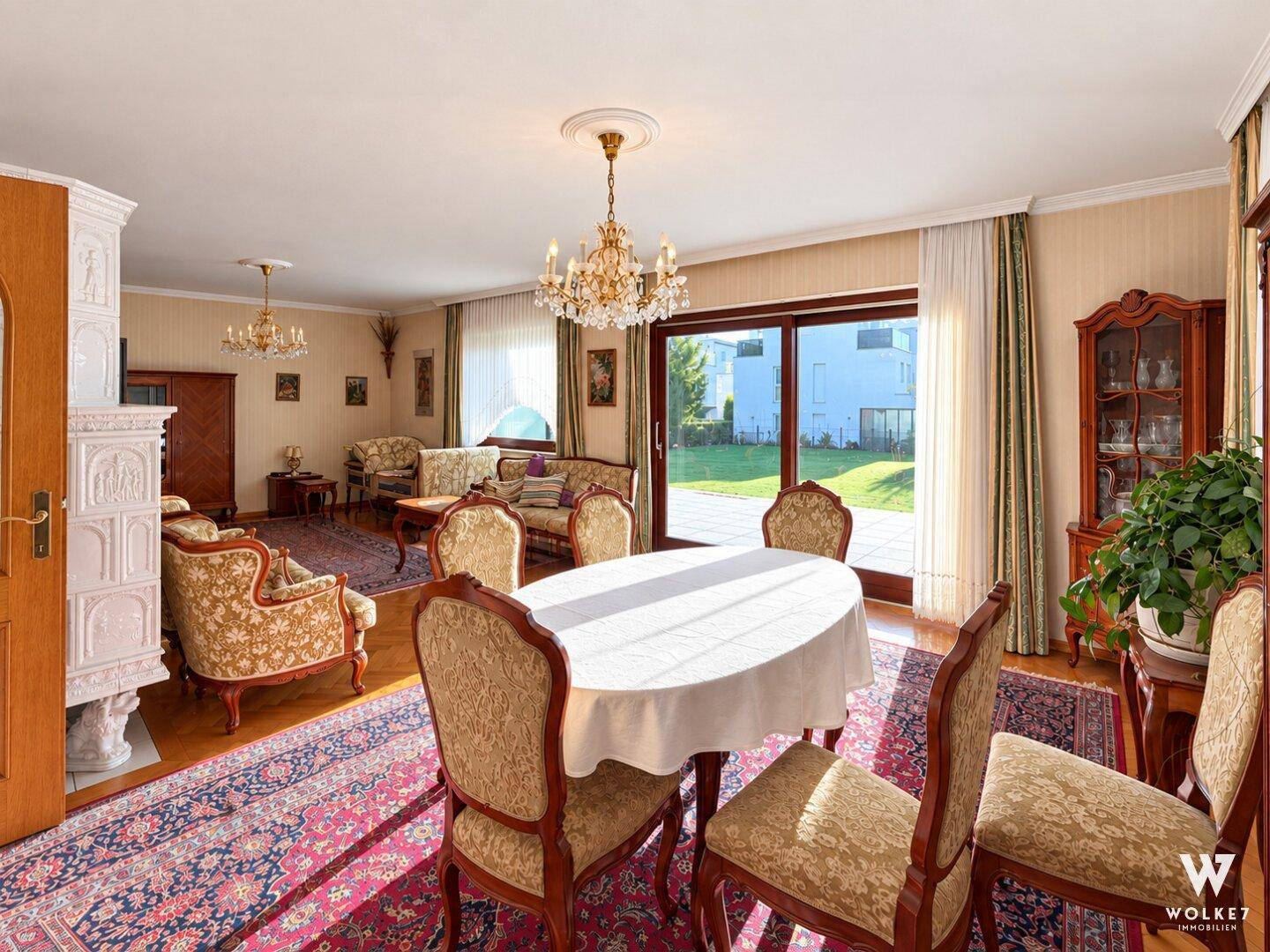 Heller Essbereich mit großem Tisch, Kronleuchter und Zugang zur Terrasse mit Gartenblick.