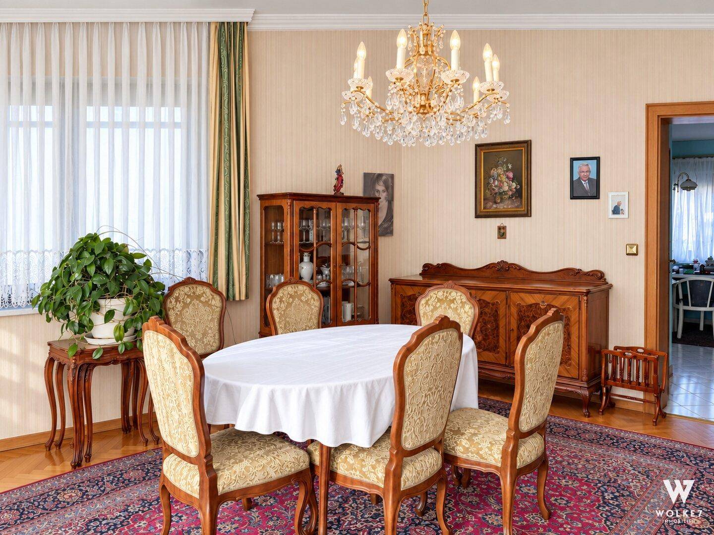 Gemütlicher Essbereich mit ovalem Tisch, klassischen Stühlen und einem opulenten Kronleuchter.