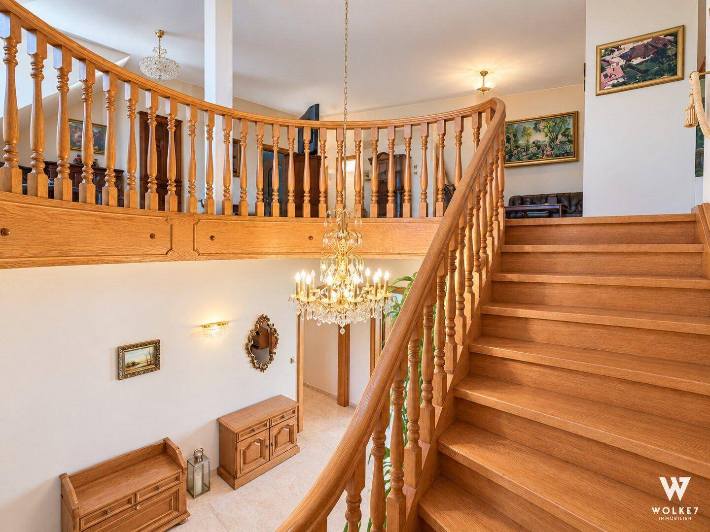 Elegante Holztreppe mit kunstvollem Geländer, die den oberen und unteren Bereich verbindet.