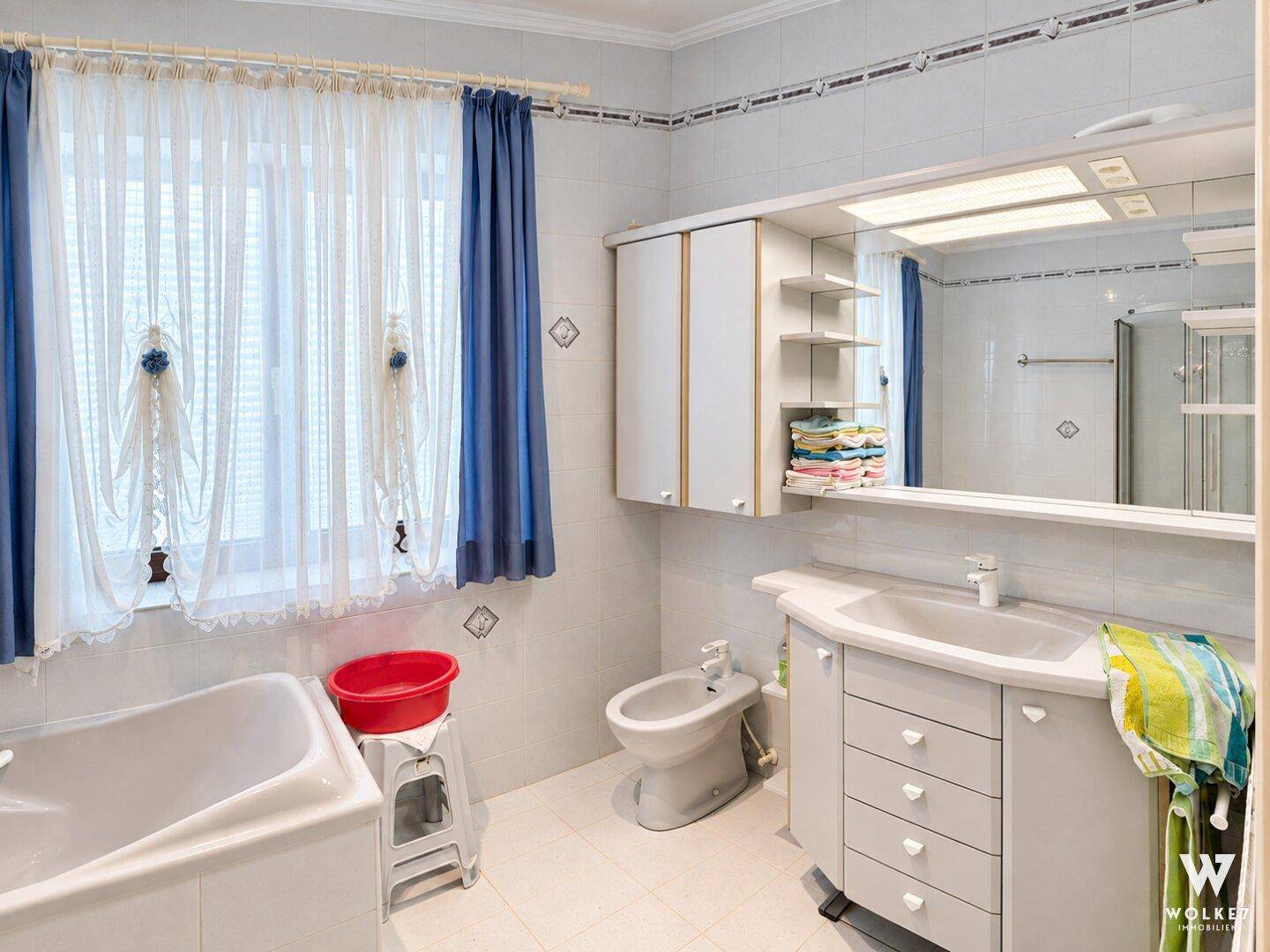 Helles Badezimmer mit Badewanne, Bidet, Waschtisch und Fenster.