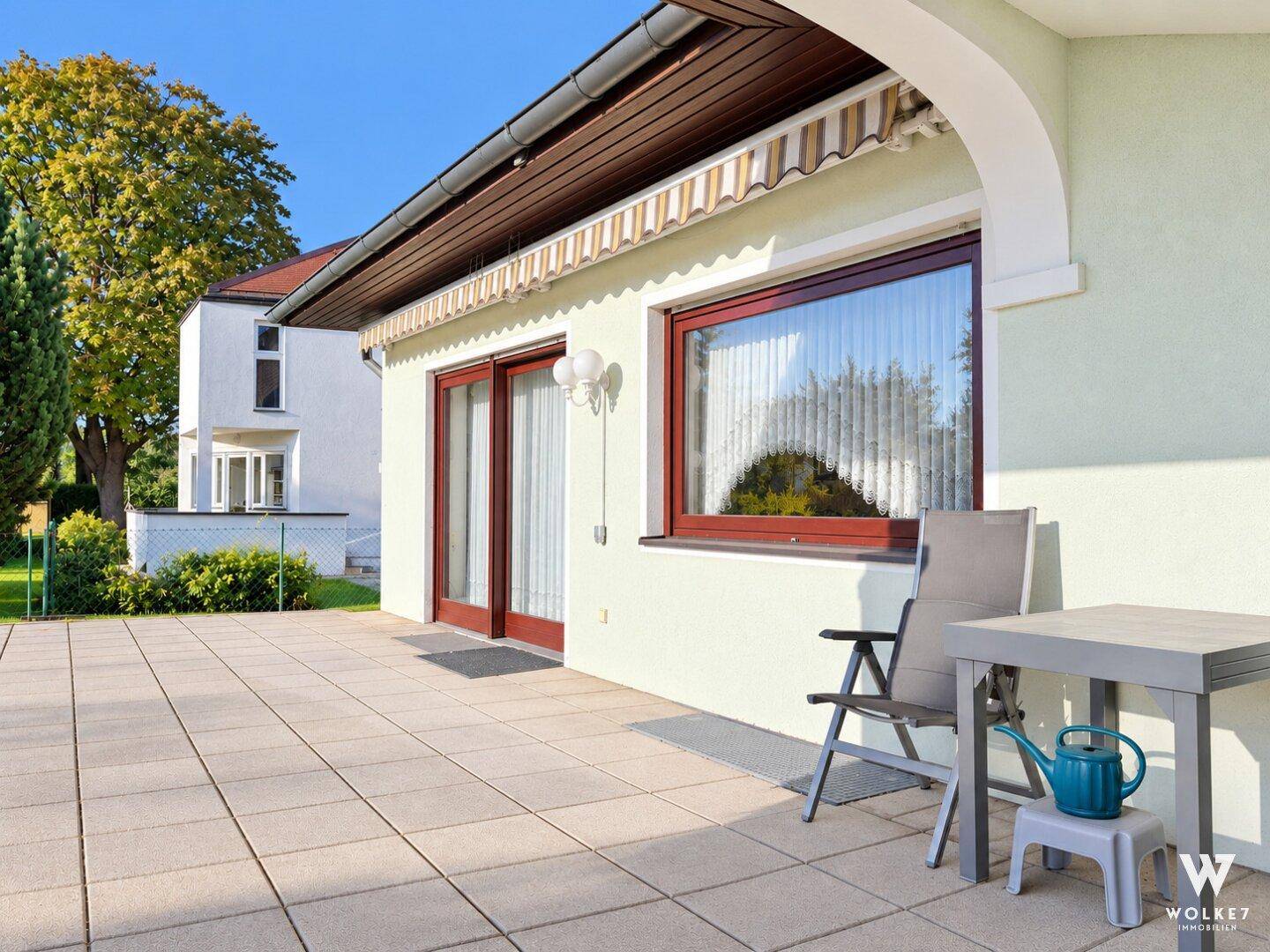 Sonniger Terrassenbereich mit Gartenmöbeln und Blick auf den gepflegten Garten.