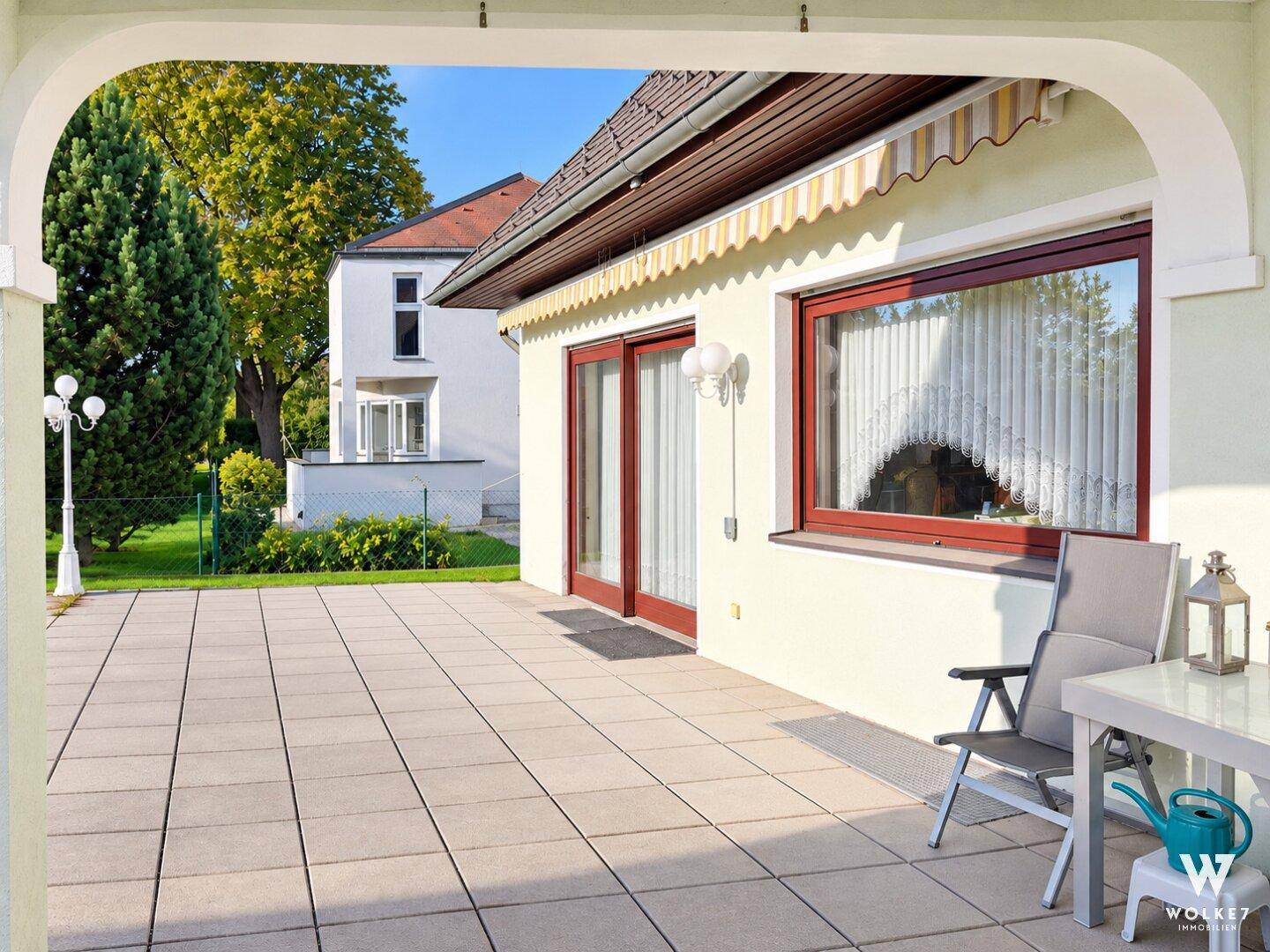 Überdachter Terrassenbereich mit Sitzgelegenheiten und weitem Blick in den Garten.