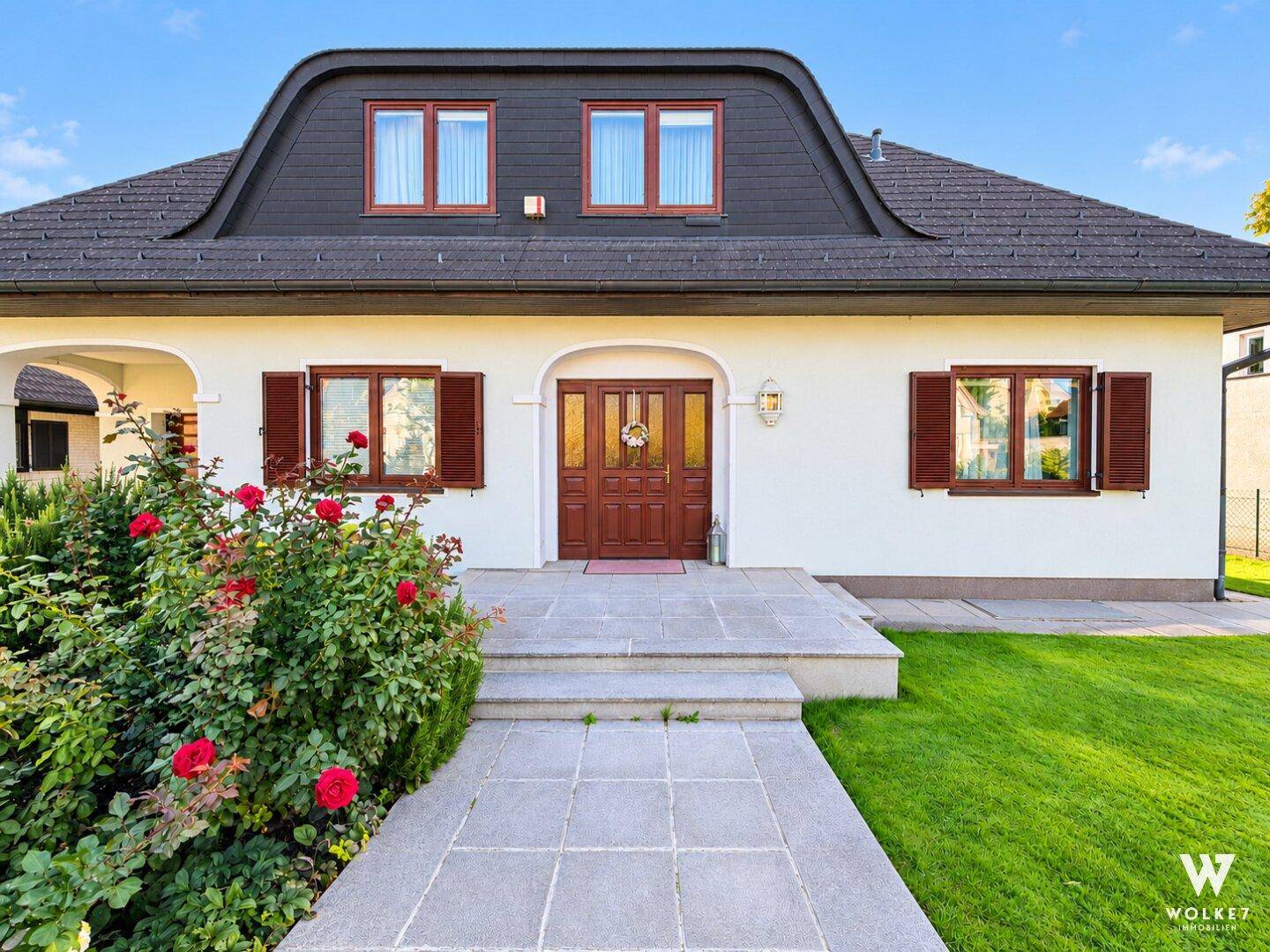 Hauptfassade des Hauses mit repräsentativem Eingangsbereich und gepflegter Vorgartenbepflanzung.