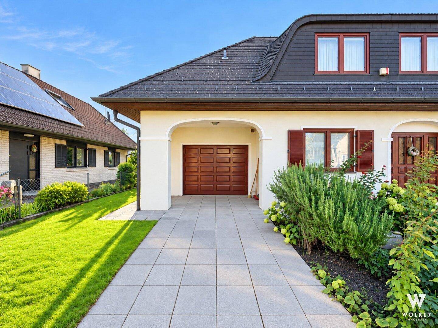 Vorderseite des Hauses mit integrierter Garage und gepflasterter Zufahrt.