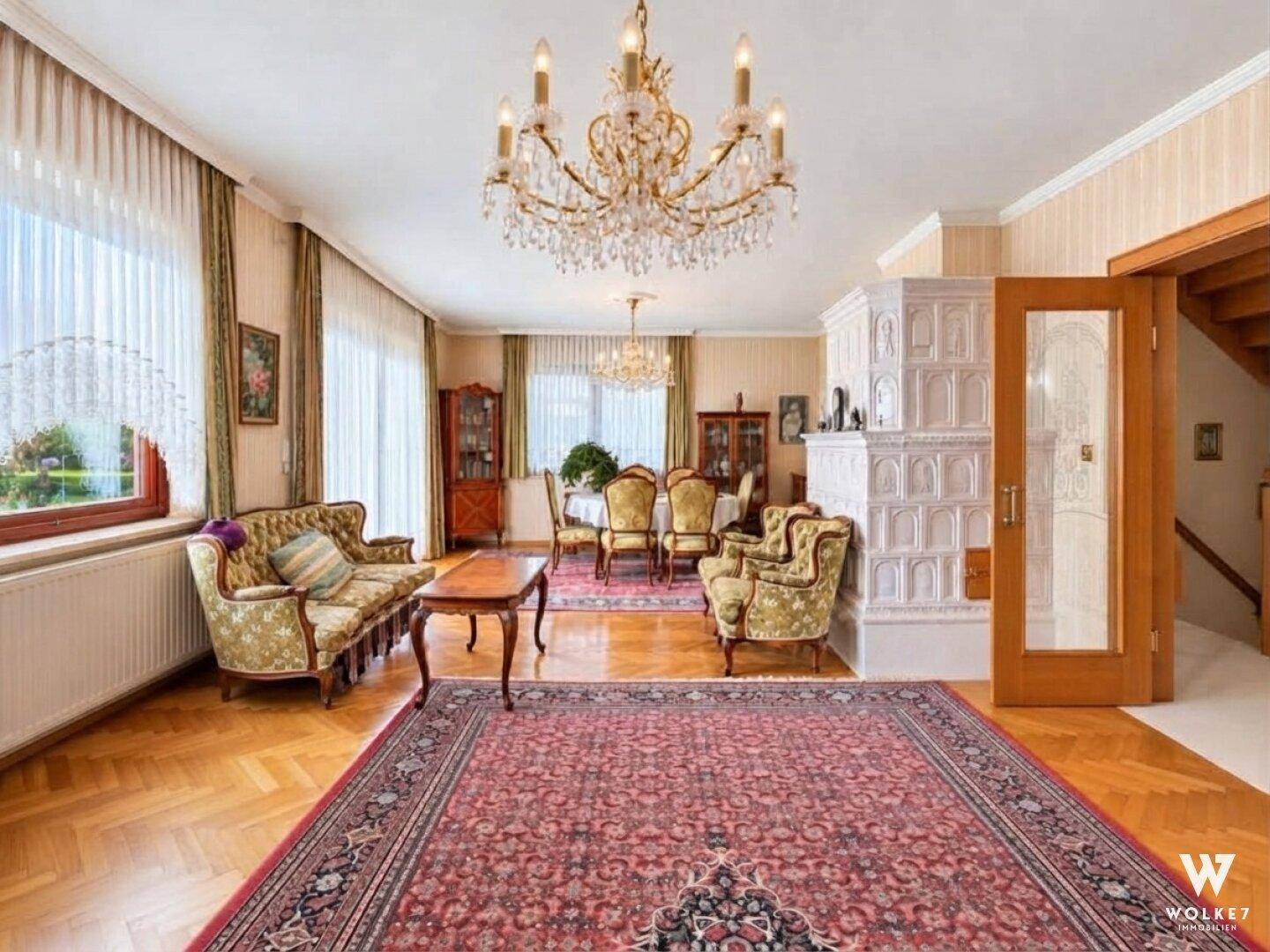Eleganter Wohn- und Essbereich mit Kachelofen, Parkettboden und Blick in den Garten.