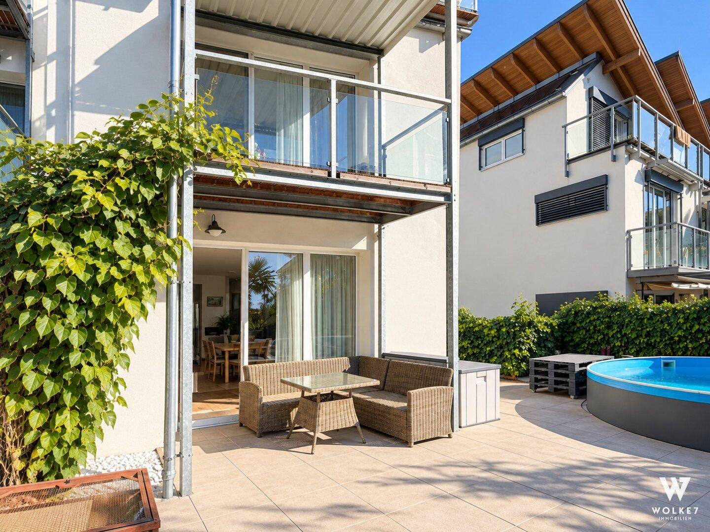 Sonnige Terrasse mit Sitzgelegenheiten und kleinem Aufstellpool im Garten.