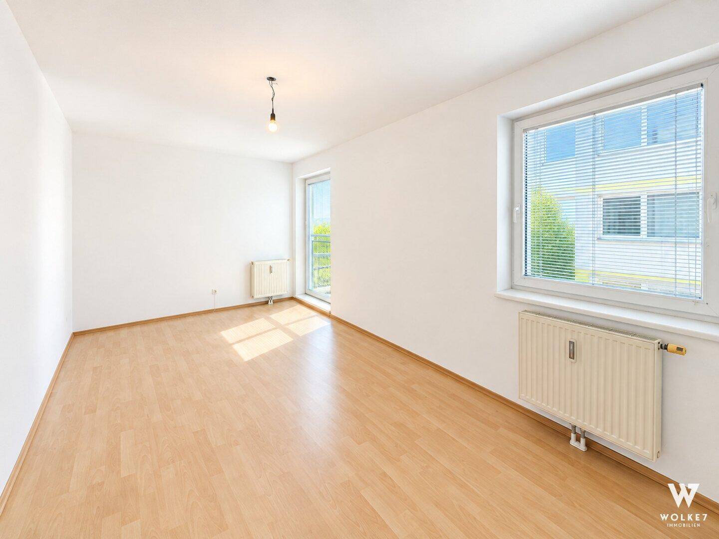 Leeres, helles Zimmer mit Laminatboden und zwei Fenstern für viel Tageslicht.