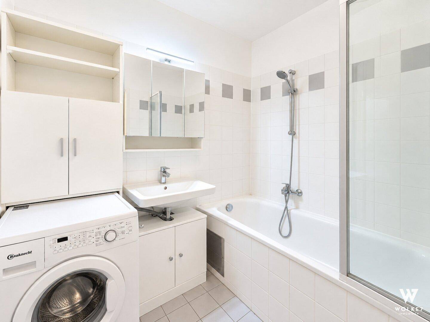 Funktionales Badezimmer mit Badewanne, Waschbecken und Waschmaschine.