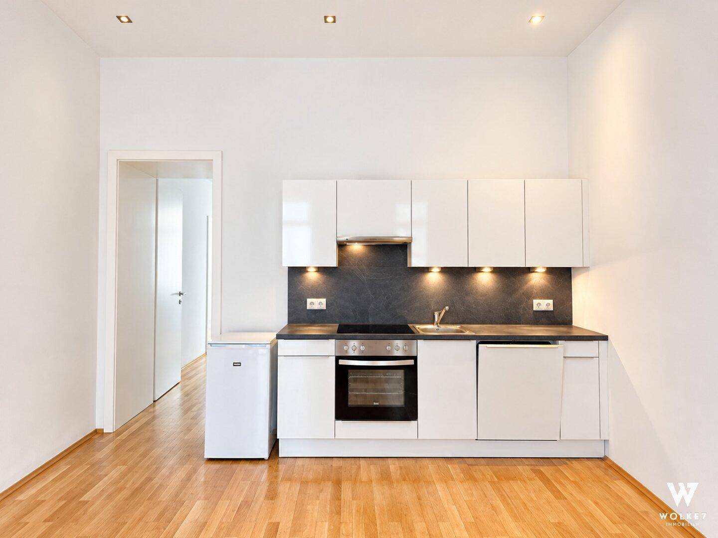 Moderne Küchenzeile mit weißen Schränken, Herd und Kühlschrank.