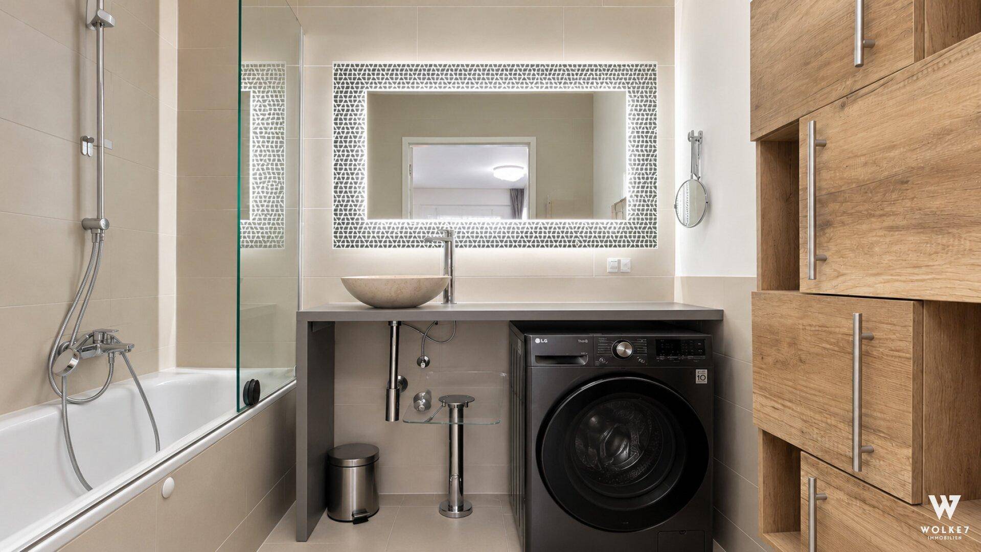Modernes Badezimmer mit Badewanne, stilvollem Waschbecken und integrierter Waschmaschine.
