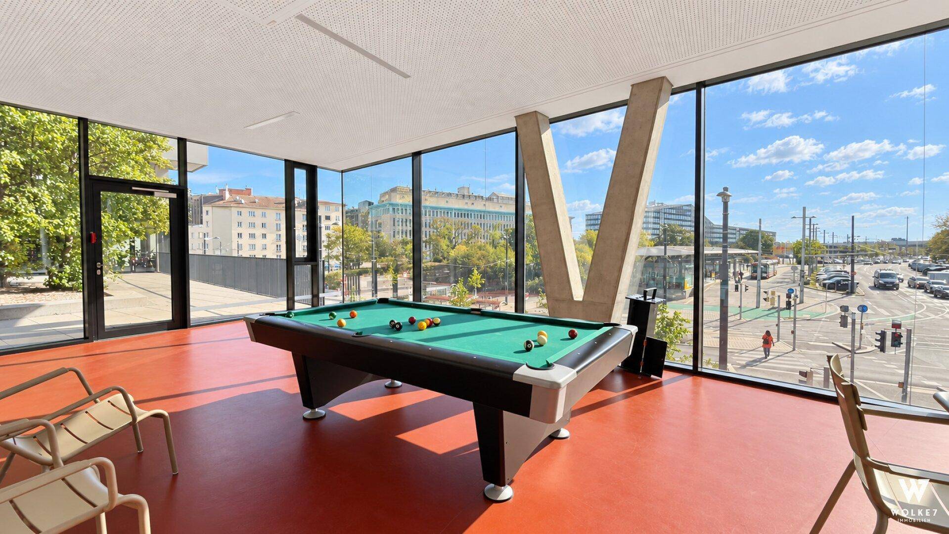 Gemeinschaftsraum mit Billardtisch und großen Panoramafenstern mit Stadtblick.