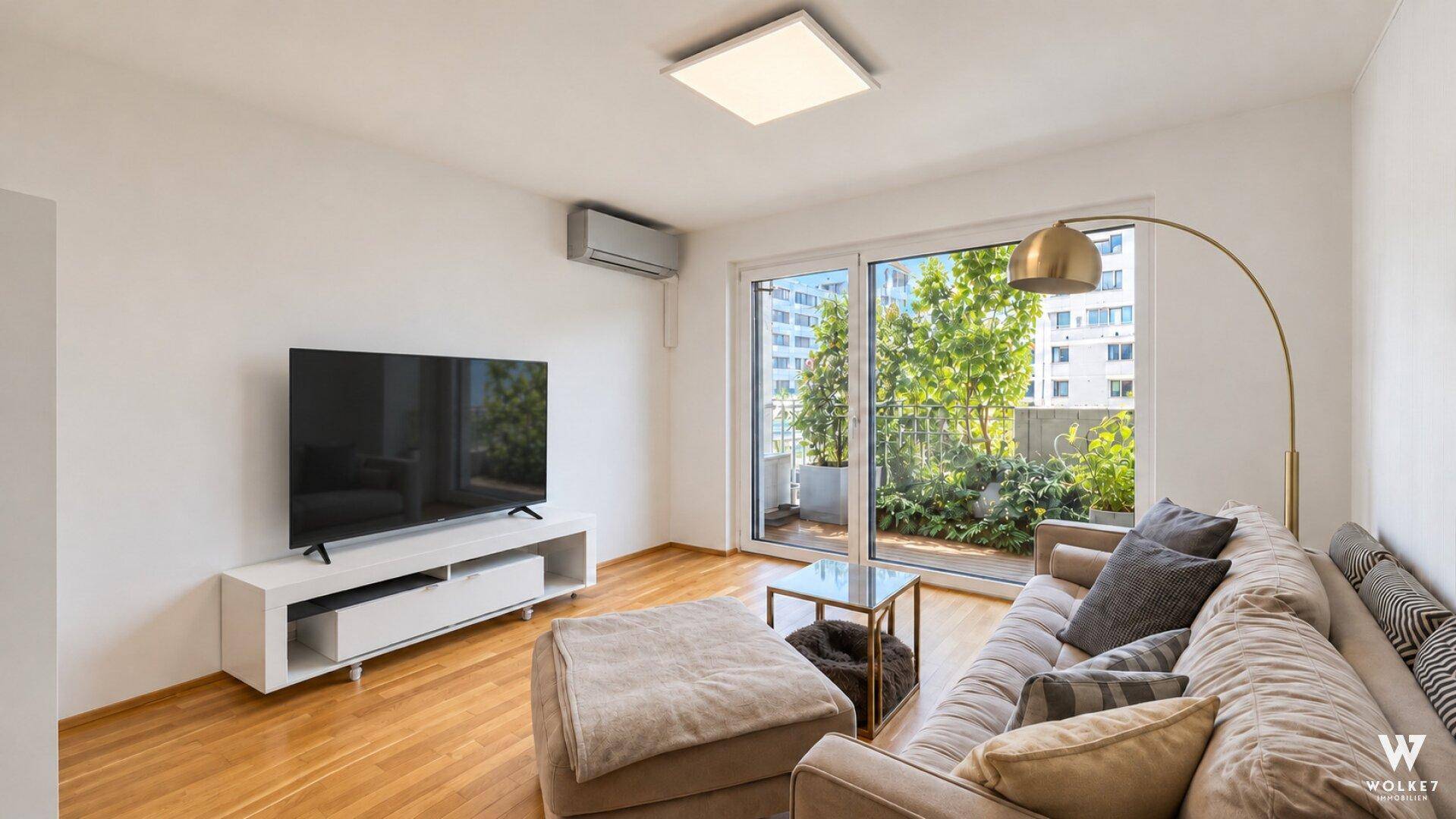 Lichtdurchflutetes Wohnzimmer mit Holzboden, großem Fenster und Klimaanlage.